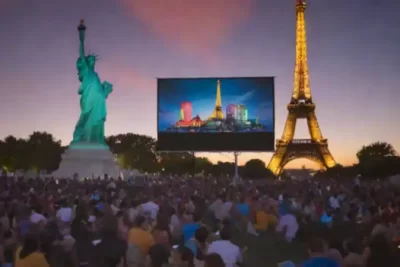 Proyección artística de cine latinoamericano con una cinta de película frente a la Torre Eiffel y la Estatua de la Libertad
