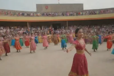 Estudiantes diversos participan en danzas tradicionales en un vibrante ambiente educativo adornado con arte folclórico y un mural de historias