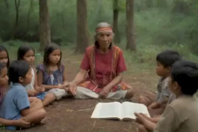 Anciano indígena enseña a niños en un entorno natural vibrante