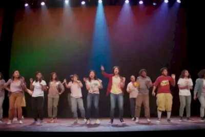Jóvenes actores diversos representan una escena vibrante en un escenario colorido