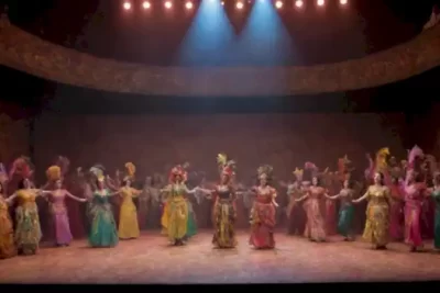 Escena teatral vibrante en América Latina con un público diverso cautivado por una actuación en un escenario decorado con colores y trajes tradicionales