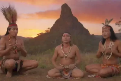 Paisaje vibrante que muestra símbolos y prácticas de culturas indígenas bajo un cielo de atardecer